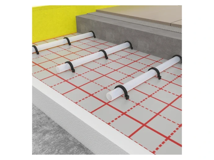 Tubes de plancher chauffant fixés par agrafes sur un film quadrillé avec isolant, avant recouvrement par la chape