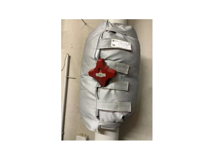 Matelas isolant VANISO posé sur une vanne, avec sangles de fermeture et volant rouge accessible